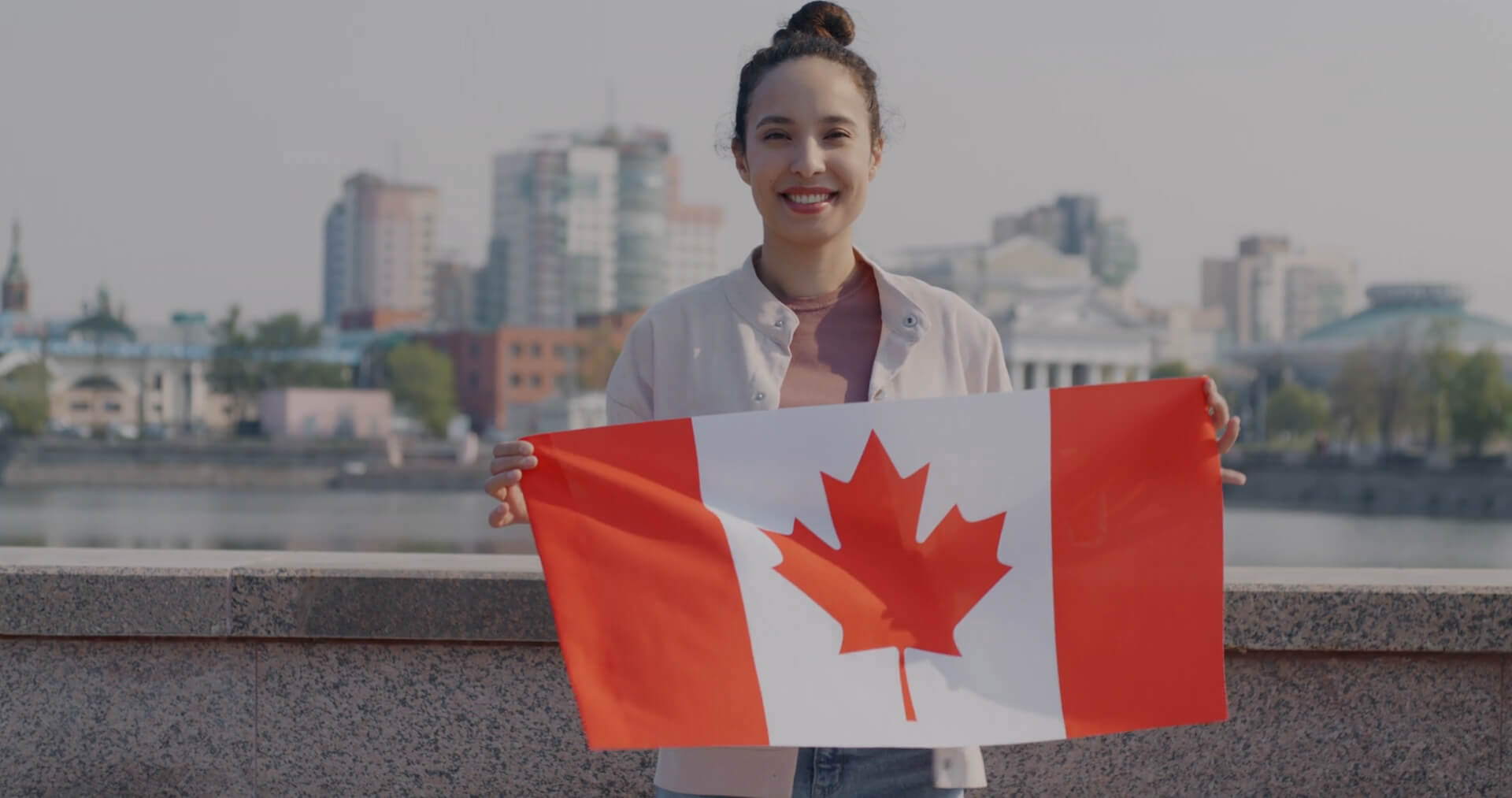 A Canadian woman holding her national flag, highlighting English as one of Canada’s official languages