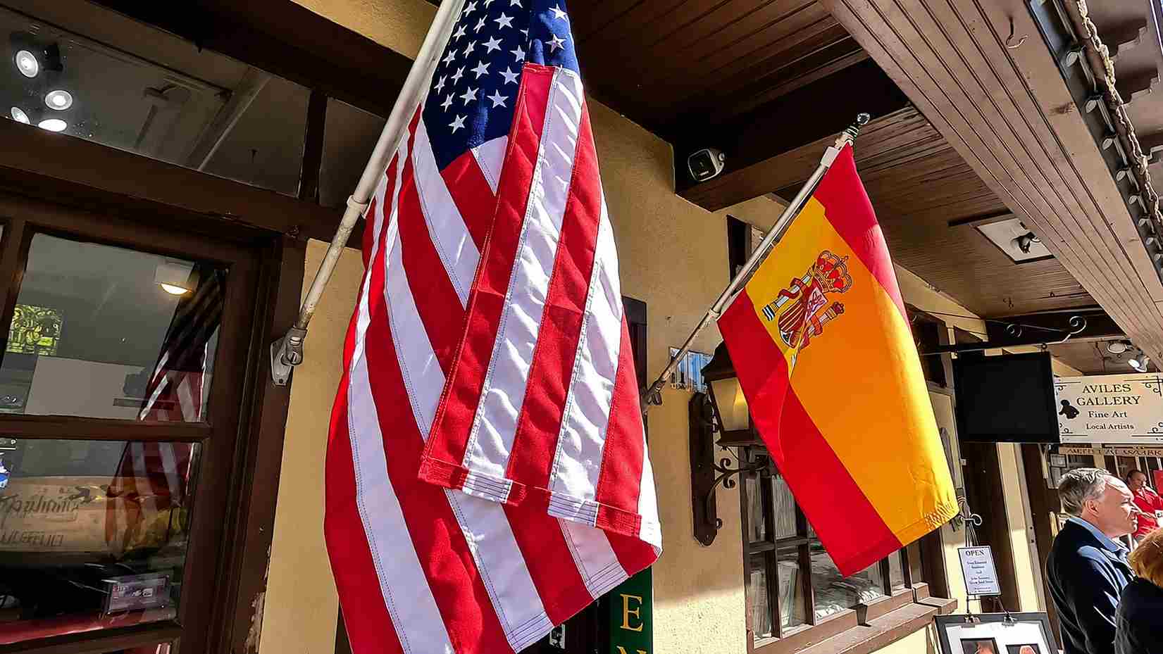 United States and Spanish flags displayed outside a storefront.